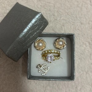 Smycken - • 1 par örhängen. • 2 ringar. •1 ”berlock”.