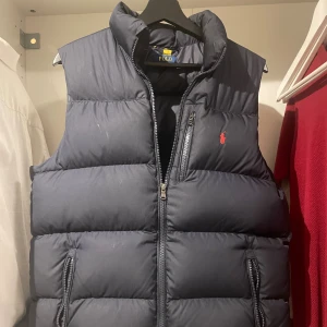 Mörkblå dunväst från Polo Ralph Lauren - Snygg mörkblå dunväst från Polo Ralph Lauren med quiltad design. Perfekt att slänga över en hoodie eller en skjorta. Skick 8/10. Pris går att diskutera.
