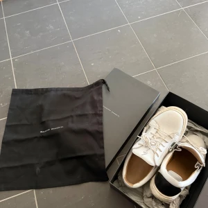 Guiseppe zanotti skor  - Ett par vita guiseppe zanotti skor med svart detalj, nypris runt 7 000kr mitt pris | 1700. Väldigt använda men i bra skick därav priset | bara höra av er vid funderingar. 