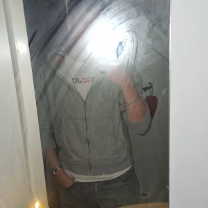 Grå Burberry hoodie zip - Säljer en grå hoodie från Burberry med dragkedja och klassiskt rutigt foder i huvan. Tröjan har snörning i huvan, två fickor fram och broderad logga på bröstet. Perfekt för dig som vill ha en stilren och lyxig vardagslook. 