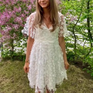 Vit blommig kortklänning med spets - Säljer min så fina studentklänning från Bubbleroom. Endast använd en gång. Skriv om ni har frågor eller prisförslag💕