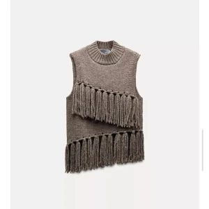 Stickad brun top med fransar - Säljer en brun stickad top med grova fransar i två diagonala rader framtill. Toppen har en hög, ribbad halsringning och är ärmlös. Perfekt för dig som vill ha en unik och trendig look.