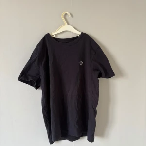 Svart t-shirt från Morris XS - En stilren svart t-shirt från Morris i storlek XS. T-shirten har en klassisk passform, rund halsringning och en liten broderad logga på bröstet. 