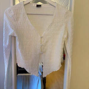 Festtopp - Säljer en vit långärmad festtopp med v-ringning och tre klädda knappar framtill. Finns en liten fläck som förmodligen går bort i tvätten!🫧🧼