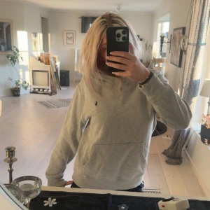Grå hoodie från Polo Ralph Lauren - Säljer en stilren grå hoodie från Polo Ralph Lauren med klassisk broderad logga på bröstet. Tröjan har huva, magficka och ribbade muddar. Strlk 14-16 år men skulle säga att den passar om man har xxs-S beroende på hur man vill att den ska sitta🩷 (nypris 1 195 på kidsbrand store)
