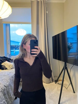 Brun ribbad topp från SHEIN - Mörkbrun ribbad långärmad topp från SHEIN med krage och knappar vid halsen. Figurnära passform och stretchigt material. Som en XS/S i storlek 