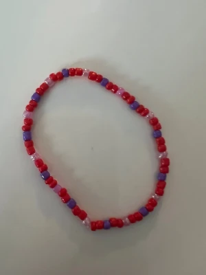  pärlarmband i rött och lila storlek S  - Ett handgjort armband med pärlor i rött och lila. 
