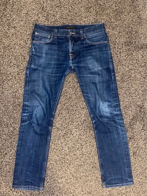 Mörkblå Nudie jeans grim tim dry deep selvage - Grim tim dry deep selvage jeans från Nudie. Storlek 32/30, grim tim jeans sitter rätt tajt så jag skulle säga att dessa är närmre 29/30 om man jämför med andra jeans. 7-8 månader gamla, inga defekter utöver lite synlig wear-tear på fickorna.