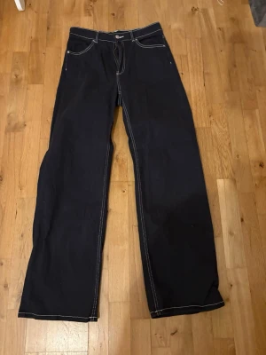 Svarta wide jeans med kontrastsömmar - Säljer ett par svarta jeans med breda ben och vita kontrastsömmar. Klassisk femficksmodell och hög midja. Perfekta för dig som gillar en loose och avslappnad stil. Materialet är kraftig jeansbomull.                              Kostar lite pågrund av att jag vill få solt dom snabbt 