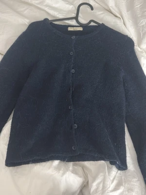 Mörkblå fluffig kofta Gina Tricot - Mysig mörkblå kofta från Gina Tricot i fluffigt material. Koftan har rund halsringning, knappar framtill och långa ärmar. Enkel och stilren modell som passar perfekt till lager på lager och ger en soft look.