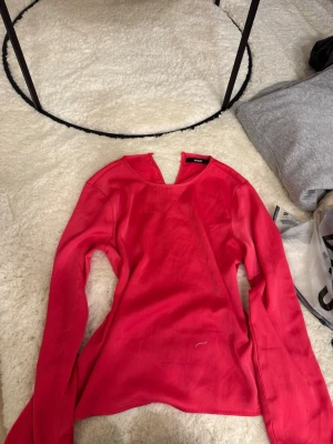 Röd långärmad topp från BikBok - Snygg rosa långärmad topp från BikBok i en enkel och stilren design. Toppen har rund halsringning och är tillverkad i ett mjukt material som känns skönt mot huden. Perfekt att matcha med jeans eller kjol för en trendig look.