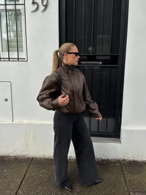 Brun oversized skinnjacka med hög krage  - Säljer en helt ny oanvänd brun oversized skinnjacka med hög krage och dragkedja framtill ifrån Berskha. Jackan är i storlek s men är oversized, jag är 160 cm och den passar mig perfect. Köptes för 559kr 