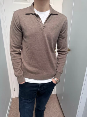 Beige långärmad tröja med krage - Snygg beige långärmad tröja med krage och knappar i halsen la chemise. Tillverkad i tunt, mjukt material som ger en clean look. Perfekt till jeans eller chinos för en avslappnad men stilren outfit.