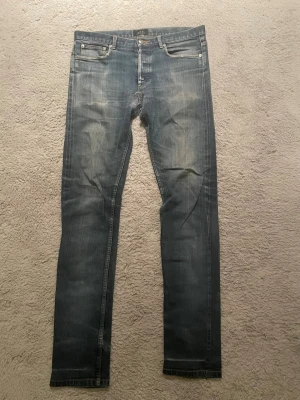 Blå raka jeans från A.P.C. - Säljer ett par klassiska blå jeans från A.P.C. i rak modell. Jeansen har fem fickor, knappgylf och snygga slitningar framtill. Perfekta för dig som gillar stilrena och tidlösa jeans. Det är selvedge och har lite lagningar på vida ställen men inget som sticker ut eller påverkar användningen.