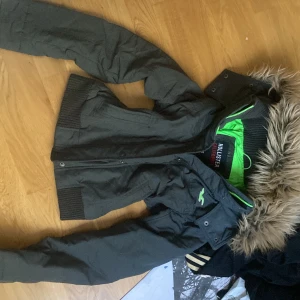 Svart Hollister jacka med pälsluva - Säljer en svart Hollister jacka i storlek S med päls på luvan och grönt foder. Jackan har ribbade muddar, dragkedja och knappar framtill. Perfekt för dig som gillar streetstyle och vill ha något som sticker ut med den gröna insidan.  PRIS GÅR DISKUTERAS!!