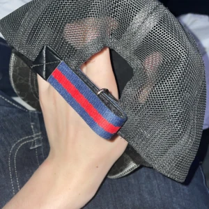 Gucci keps med orm och GG-mönster - Säljer en svart Gucci keps med klassiskt GG-mönster och en fet röd och vit orm på framsidan. Baksidan är mesh och har justerbart band med blå och röd rand. Materialet är polyester och bomull, perfekt för dig som vill sticka ut med lyxig streetstyle. Kan gå ner i pris vid snabb affär 