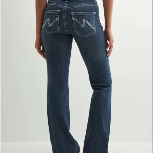 Low waist bootcut jeans Nelly - Snygga blå jeans med bootcut passform och låg midja. Jeansen har snygga  detaljer på bakfickorna och dubbla knappar på framsidan. Köpta på Plick och använd två gånger sen dess, förra ägaren använde dem knappt!💓