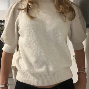 Vit stickad tröja från Vero Moda - Mysig vit stickad tröja från Vero Moda med puffiga halvlånga ärmar och ribbade muddar. Tröjan har en klassisk rund halsringning och är perfekt för lager-på-lager-stil. Väldigt bra skicka och använda fåtal gånger💕
