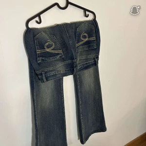 Blå bootcut jeans från SHEIN, stl 32 - Säljer ett par blå bootcut jeans från SHEIN i storlek 32. Jeansen har snygga broderade bakfickor med gul tråd och klassisk femficksdesign. Materialet är jeans med lite stretch för extra komfort. Perfekta för dig som gillar en avslappnad men trendig look.