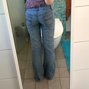 Blå bootcut jeans med dragkedjor - Säljer ett av mina älsklingsjeans 🦊<33 vintage, lågmidjade, bootcut med snygga dragkedjor längs utsidan av benen och coola broderade detaljer på bakfickorna. De är ljusblå och lite vitrandiga😍 Jag är 160 cm lång för referens<3 