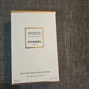 Coco Mademoiselle Eau de Parfum 100ml - Lyxig parfym från Chanel, Coco Mademoiselle Eau de Parfum Intense i en elegant, rektangulär glasflaska med transparent lock och guldiga detaljer. Doften är intensiv och feminin, perfekt för dig som vill sticka ut med en klassisk och modern touch.