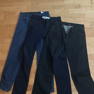 3 par jeans jeans i blå och svart - Säljer tre par snygga jeans från J.Lindeberg (2 st) och newlook i olika blå och svarta nyanser. Klassisk femficksmodell med raka ben och kontrastsömmar. Jeansen är tillverkade i bomull med en skön passform och stilren look, perfekta för dig som gillar enkel och clean stil. VIKTIGT: Midjan är smallare än vad storleken säger så en person med något smalare midja kommer in i dessa! Nypris för alla är över 3000kr!
