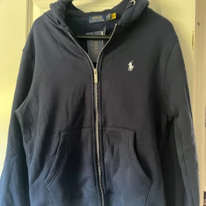 Mörkblå hoodie från Polo Ralph Lauren - Säljer helt ny kofta från polo Ralph lauren storlek m aldrig använd påse prislapp med mera ingår. Hör av er vid frågor och funderingar 