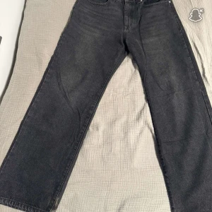 Svarta straight jeans  - Säljer ett par svarta jeans från Levi's med klassisk straight passform. Jeansen har fem fickor, knapp och dragkedja fram samt en mörk tvätt som ger en cool vibe. Perfekta för dig som gillar tidlös stil och vill ha ett par jeans som funkar till allt.