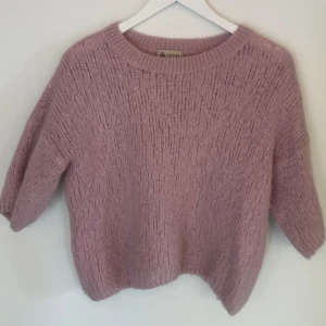 stickad tröja från Chelsea - Supermysig ljuslila/rosa stickad tröja från Chelsea med rund halsringning och trekvartsärmar. Krymt lite i tvätten men inget som märks tydligt, strl s/xs.
