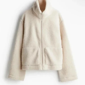 teddyjacka hm - Mysig beige teddyjacka med hög krage och hel dragkedja framtill. Jackan har två stora fickor och är tillverkad i fluffigt teddy-material som håller dig varm under kyliga dagar. Storlek M men passar s 