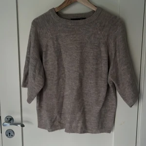 Beige stickad tröja från 157 - Mysig beige stickad tröja från lager 157 med rund halsringning och trekvartsärm. Tröjan har en avslappnad passform och ribbade muddar vid hals, ärmslut och nederkant. Aldrig använd.