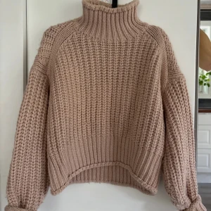 Beige stickad polotröja från H&M - Supermysig beige stickad polotröja från H&M i chunky garn. Tröjan har hög krage, lång ärm och ribbade muddar. Perfekt för lager-på-lager och ger en chill oversized vibe. Passar dig som gillar en enkel men trendig look.