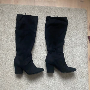 Svarta höga stövlar med klack - Säljer ett par svarta höga mocka stövlar, i storlek 36. Nästan helt oanvända eftersom de är för små för mig.