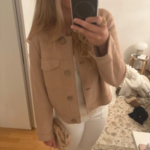 Beige ulljacka från Gerry Weber - Storlek 40 men passar s-m. Säljer en snygg beige jacka från Gerry Weber i ullmix. Jackan har klassisk krage, stora bröstfickor och knäppning med knappar framtill. Modellen är boxig och croppad, perfekt till jeans eller kjol. Enkel och stilren design som är lätt att matcha. 