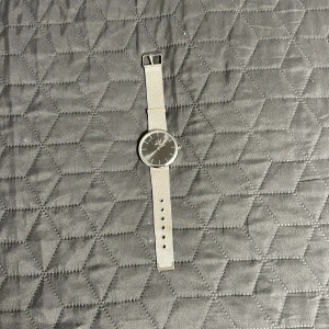 Silverfärgad Calvin Klein klocka - Stilren klocka från Calvin Klein med rund svart urtavla och silverfärgat mesh-armband i rostfritt stål. Minimalistisk design med tydliga index och diskret CK-logga på urtavlan. Perfekt accessoar för en clean look.