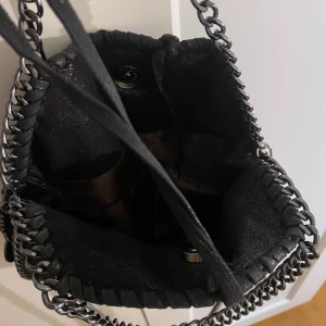 Svart väska - Säljer en jätte fin Stella McCartney liknade väska med 3 fack. En tråd är lös (visas på bild) men går att lägg in i väskan så den inte syns💕
