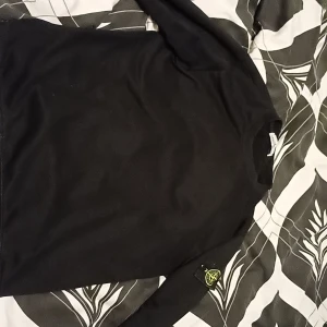 Svart långärmad tröja från Stone Island - Svart långärmad tröja från Stone Island med klassisk rund hals och ikonisk logotyp-patch på ärmen. Tröjan har en clean och stilren look, perfekt till jeans eller cargobyxor. Materialet känns mjukt och bekvämt mot huden. Pris kan diskuteras!!