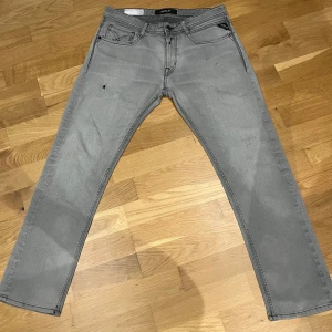 Gråa Replay Jeans - Säljer ett par snygga Replay jeans i grå tvätt. Jeansen har en modern, något slim passform som sitter snyggt utan att bli för tighta. Klassisk femficksmodell med dragkedjegylf och Replay-logga på fickan. W30/L30