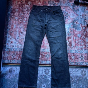 Gråa raka jeans från McGordon - Säljer ett par mörkgråa jeans från McGordon med klassisk femficksdesign och raka ben. Jeansen har normal passform och är tillverkade i ett slitstarkt jeanstyg. Perfekta för dig som gillar en enkel och tidlös look. Är inte utsvängda men ger looken av utsvängda jeans.