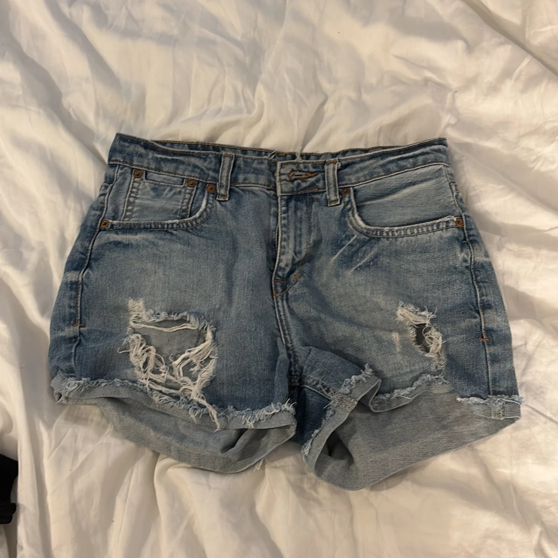 Blå jeansshorts med slitningar