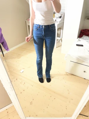 Blå jeans från Gina Tricot, strl 38 - Säljer ett par klassiska jeans från Gina Tricot i storlek 38. Modellen har hög midja och raka ben med en straight fit. Jeansen är tillverkade i jeansmaterial och har fem fickor samt knapp och dragkedja framtill. Modellen är 172cm lång.