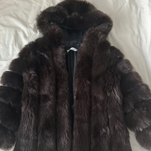 Mörkbrun pälsjacka från Borninstockholm - Jättefin mörkbrun pälsjacka från Borninstockholm i storlek S men passar även M. Jackan har huva, breda ärmar och stängs med krok knappar. Har fickor, varm och skön. Använd 3 gånger men fortfarande i ny skick. Inga skavanker. Perfekt statement piece för kalla dagar och ger en lyxig vibe till din outfit. Ord pris 2699kr.