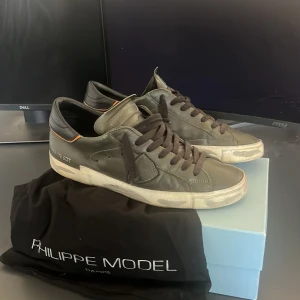 Philippe Model Olivgröna sneakers i skinn - Snygga Olivgröna Philippe Model sneakers i skinn med Svarta snören. Skorna är i storlek 43 och passar även 42. Det är lite deffekt på sulan som ni kan se på bilden. Klassisk låg modell med diskret logga på sidan och orange detalj vid hälen. Kommer med originalpåse och box. Perfekta för dig som gillar stilrena och exklusiva sneakers. Pris kan diskuteras dm!!!