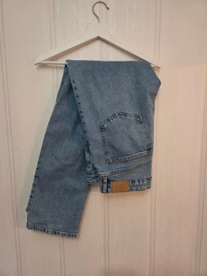 Ljusblå jeans från Gina Tricot - Säljer ett par ljusblå jeans från Gina Tricot med vida ben. Midjan är midwaist i stl 42, stor i midjan men lite tajtare runt låren, aldrig använda. Nypris 500kr