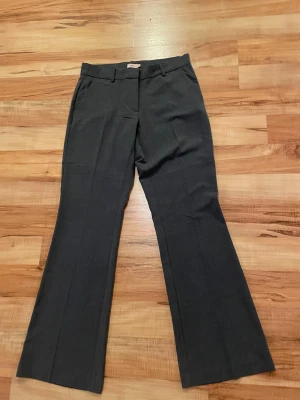 Mörkgrå kostymbyxor från Nelly - Snygga mörkgrå kostymbyxor från Nelly i klassisk modell med raka ben och bootcut.