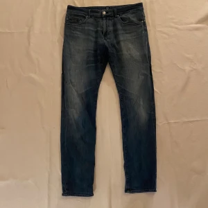 Hugo Boss Jeans - Säljer ett par riktigt snygga jeans från Hugo Boss. Jeansen har en snygg wash, metalldetaljer och en riktigt bra passform. Ett mycket bra vardagsplagg som går till det mesta. Storleken är w34 l34. Vid intresse är det bara att höra av sig :)