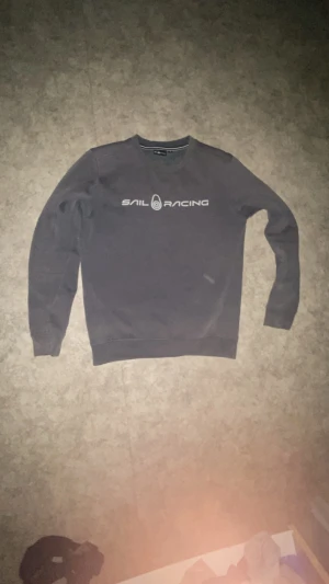 Mörkgrå Sail Racing sweatshirt - Snygg mörkgrå sweatshirt från Sail Racing med vit logotyp tryckt över bröstet. Tröjan har rund hals, långa ärmar äkta köpt för 900 pris kan diskuteras 