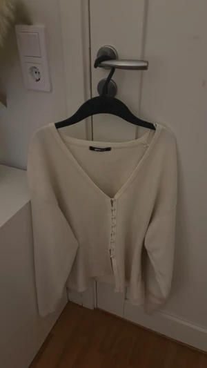 Beige kofta från Gina Tricot - Snygg beige kofta från Gina Tricot i storlek M. Koftan har v-ringad hals, långa ärmar och knappar framtill. Mjuk stickad känsla och loose passform som ger en chill vibe. Perfekt att slänga på sig när det är lite kyligt ute.