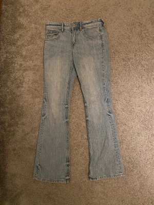 Bootcut jeans från H&M - Ljusblåa bootcut jeans från HM i storleken 158 barn med låg midja och fickor som går att knäppa. Använda enbart några fåtal gånger och inga tecken på användning. Frakt tillkommer🥰🎀