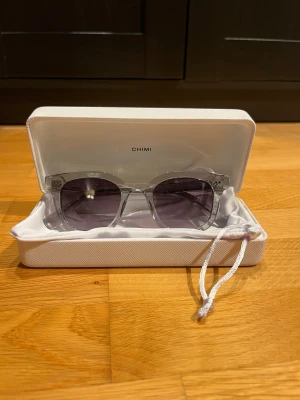 CHIMI 02 solglasögon  - Snygga solglasögon från CHIMI med transparent fyrkantig båge. Glasen är mörktonade i grått och ger en clean look. Kommer med originalfodral och påse. Perfekta för dig som vill sticka ut med stilrena accessoarer. Nypris (1400)  andvänt fåtal gånger. 
